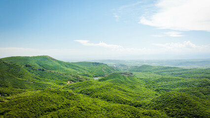 Rolling green hills and a hidden lake seen from above, with clouds casting soft shadows. Peaceful natural landscape in Georgia