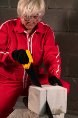 A woman is concentrating on cutting a brick.