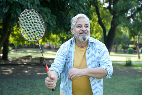 Indian senior man playing badminton in the park having fun outdoor sports and game activity concept. copy space