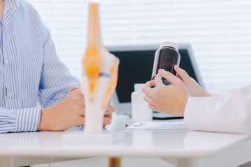 Orthopedic surgeon shows knee model to patient in human knee hospital. Knee joint diseases and...