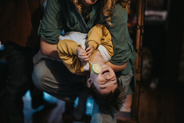 A candid and cheerful photo capturing a young child laughing while being playfully held upside down...