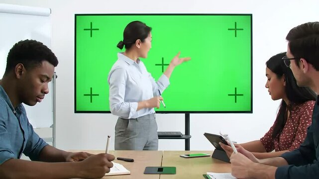 Business team meeting with female presenter and green screen display in conference room