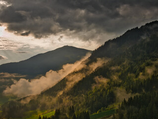 Foggy morning in the mountains, dark cloud, sun
