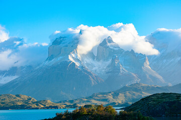 Morning light on the iconic Cuernos del Paine peaks, partially covered by clouds, in Torres del...