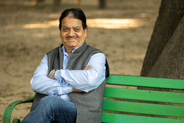 Obraz premium Indian happy Senior man sitting and smiling at park