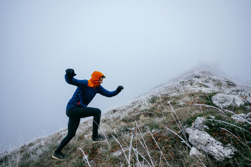 Man Climbing Rocky Hill in Fog