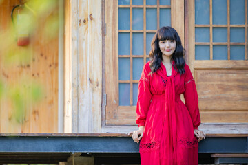 Asian woman in red dress resting carefree, relaxing on sunny day. Beautiful woman smiling at the park.