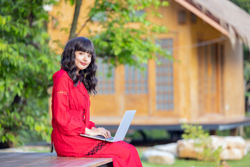 Beautiful asian businesswoman sitting on the terrace with laptop on legs. Woman working from home using computer laptop.