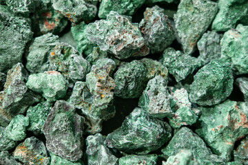 Close-up view of rough green gemstones scattered on a surface, showcasing their unique textures and natural formations, ideal for mineral enthusiasts and collectors