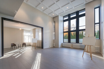 Modern architectural design of a living room in a country house, unfurnished. High ceiling .Large windows, parquet floor. The interior design is presented on an easel.