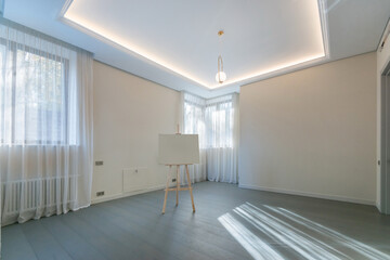 Bright bedroom with parquet floor and curtains on the windows, unfurnished. The interior design is presented on an easel.