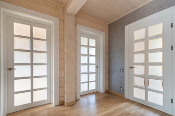 Obraz premium Modern design of the hall, decorated with a beam of light wood. White doors with glass windows.