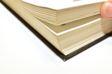 A man's hand turns the pages of a book lying on the table.