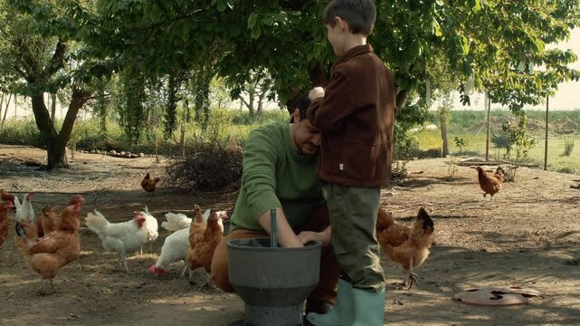 Farmer Man and Son with Chickens in Village Coop