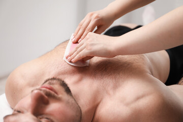 Young man undergoing wax epilation in salon, closeup