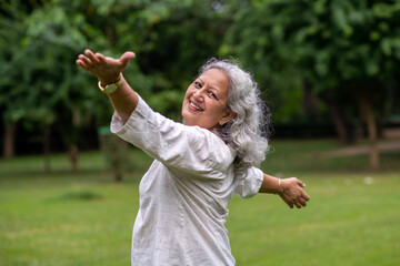 Indian happy senior woman spread her arms in environment nature like the wings of a bird....