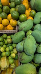 Closeup of market stall of delicious fresh tropical fruits of mango, oranges and limes in Bali Indonesia