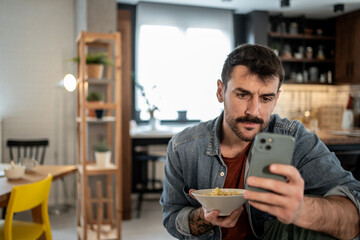 Man eating breakfast while checking smartphone