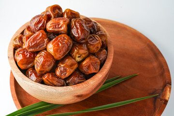 Dates fruit sukari or kurma sukari, in wooden bowl isolated on white background