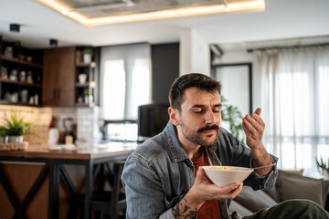 Man savoring delicious pasta in modern kitchen