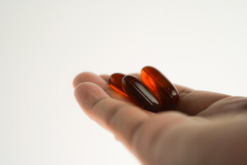 Male hand holding Oil filled capsules, softgel of food supplements, fish oil, omega 3, vitamin E