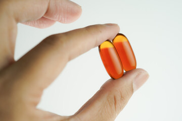 Male hand holding Oil filled capsules, softgel of food supplements, fish oil, omega 3, vitamin E