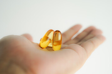 Male hand holding Fish oil capsules with omega 3, omega 9, vitamin D, vitamin E, Cod liver oil