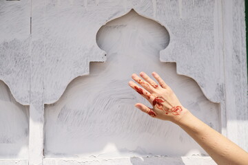 Woman’s hand adorned with a henna tattoo, posed against the backdrop of a traditional Arabian arch, Oman