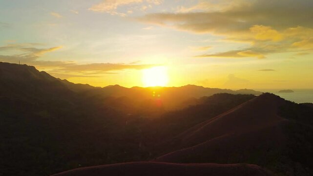 Golden sunrise rises over the hills near Mount Tapyas in Coron with warm light silhouettes and layered tropical ridges above Palawan