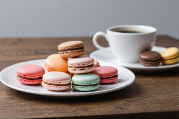A plate of colorful macarons served with a cup of coffee, perfect for a cozy morning or afternoon