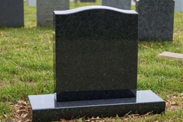 A black granite headstone in a peaceful cemetery setting