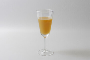 A clear glass filled with orange juice sits on a wooden table, ready to be enjoyed