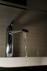 Shiny faucet with water flowing in a clean bathroom sink