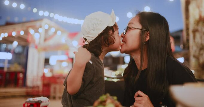 Playful and loving moment of a child sharing French fries with mom, highlighting the deep emotional bond in everyday family life.

