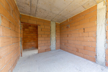 Unfinished room interior of building under construction. Brick red walls. New home.