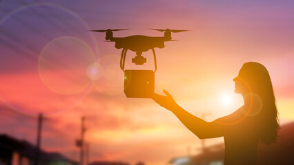 Silhouette of a Woman Receiving a Delivery from a Drone at Sunset