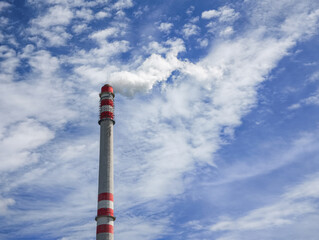 Industrial chimney emitting smoke into cloudy blue sky in Prague