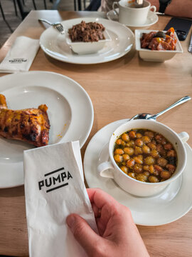 Prague, Czech republic - May 4, 2025: Customer holding napkin enjoying meal at restaurant Pumpa with roasted chicken and chickpea soup