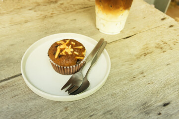 Chocolate almond cup cake with iced coffee on table.