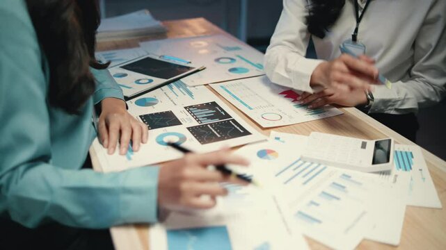 Two business professionals collaborate on financial documents, analyzing data and charts during a meeting to strategize decisions and improve company performance