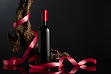 Bottle of red wine on a black reflective background.
