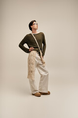 Fashionable non binary individual showcasing unique style in a minimalistic studio