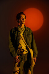 Fashionable non binary individual posing against a vivid sunset background