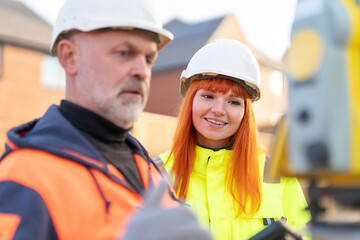 Construction workers collaborate while reviewing data on tablet at building site