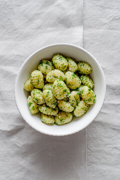 Portion of potato gnocchi with basil &lsquo;Pesto&rsquo; sauce, on light gray background. Italian food.