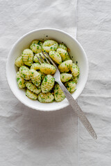 Portion of potato gnocchi with basil ‘Pesto’ sauce, on light gray background. Italian food.