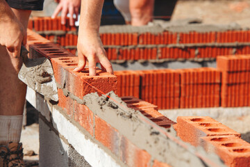 Construction worker bricklayer lays bricks for new structure at building site using tools and materials for masonry work