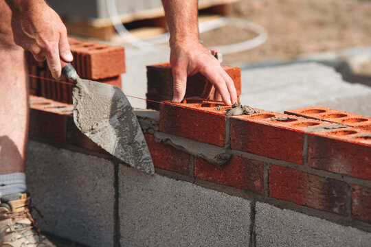 Construction worker bricklayer lays bricks for new structure at building site using tools and materials for masonry work