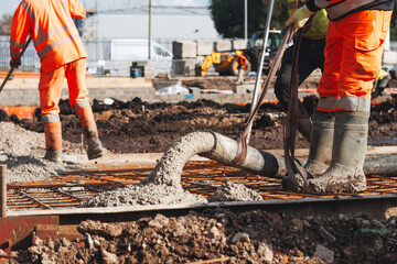 Close-up of Concreters builders using concrete pump to pour wet concrete at building site