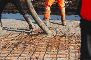 Construction worker pouring concrete onto reinforcing mesh at a building site